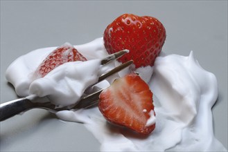 Strawberries on a fork with whipped cream