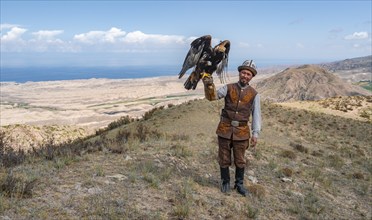 Traditional Kyrgyz eagle hunter hunting in the mountains in a dry landscape, near Kysyl-Suu, Issyk