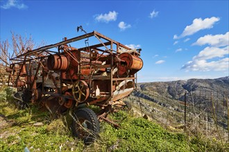 Rusty old combine harvester in front of a picturesque mountain landscape and blue sky, wrecked