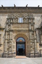 Entrance of a baroque building with richly decorated stone carvings and sculptures above the door,