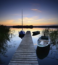 Quiet lake with jetty and boats after sunset at dusk, Großer Lychensee, Lychen, Brandenburg,