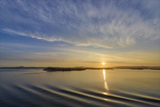 Calm seascape at sunrise with soft clouds and island in the background, Bergen, Vestland, Norway,