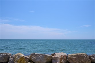 View of the calm Mediterranean Sea and blue sky, rocks in the foreground, Saintes-Maries-de-la-Mer,