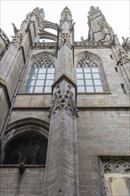 Detail of a Gothic church structure with richly decorated windows and stone ornaments, Le