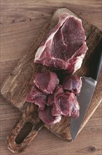 Raw beef meat, sliced on a cutting board, with a knife, no spices, no herbs, top view, wooden