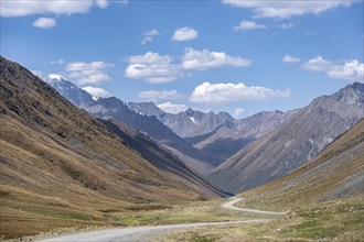 Gravel track in a valley, picturesque mountain landscape with white mountain peaks, Tian Shan