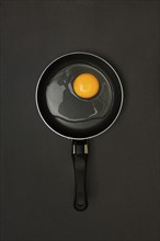 Cracked egg in pan, dark background