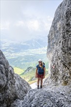 Female mountaineer with helmet climbing a rock face, ascent to the Ackerlspitze, Wilder Kaiser,