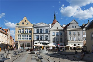 Historic market square with cafés and pigeons, surrounded by impressive architecture, Market