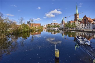 River Trave with quay wall, historic houses, Lübeck Holstentor, church towers of St. Marien and St.