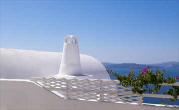 White building with traditional architecture in front of the blue sea and sky, surrounded by