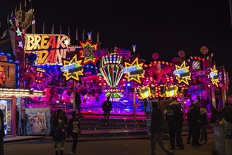 A colourful illuminated carousel at a funfair at night, impressing with bright colours and neon