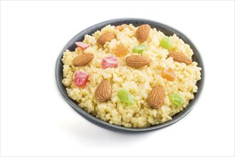 Millet porridge with candied fruits and almonds in blue ceramic bowl isolated on white background.