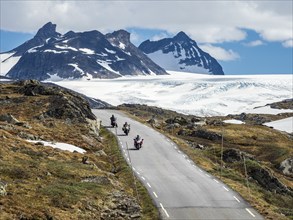 Group of motorcyclists on mountain crossing Sognefjellsvegen, view towards glacier, mountain pass