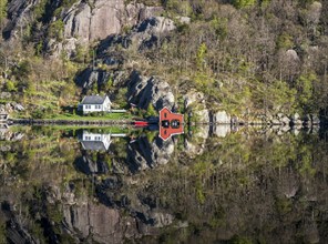 Fjord near Ana Sira at the norwegian southern coast, lonely houses at the foot of a rock formation,