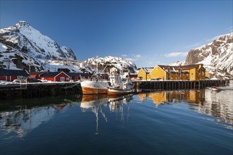 Fishing village with yellow and red houses in front of snow-covered mountains, Nusfjord,