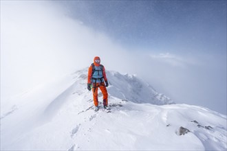 Ski tourer in snowy mountain landscape, at the summit of the Wildhorn, cloudy mood, high tour,