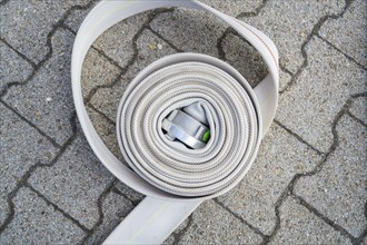 Coiled fire hose with metal buckle on paved ground, fire brigade, Enzklösterle, Black Forest,