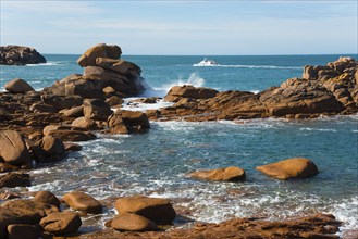 Boat navigating between majestic rocks on a calm coast, Ploumanac'h, Ploumanach, Perros-Guirec,