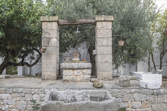 An old stone fountain surrounded by trees conveys a rustic and rural charm, Apulia, Italy, Europe