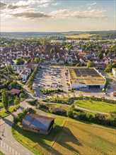 View of the outskirts with a large car park and shopping centre, surrounded by fields and hills,