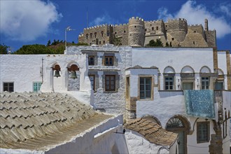 Castle above traditional white houses, under a clear sky with bright sunshine and medieval