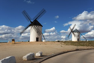 Two windmills on a hill under a blue sky with clouds, Campo de Criptana, Ciudad Real province,