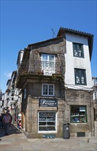 Rustic old stone house with balconies and a shop in an urban environment, house in Rúa do Vilar,