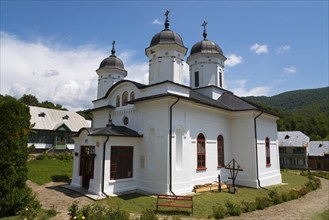 White church with several domes and crosses under a sunny sky, Orthodox nunnery Suzana, Maneciu,