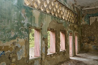 Dilapidated building with colourful, peeling paint and graffiti, whose many windows expose a