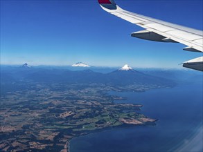 Aeroplane wing with view over snow-capped volcanoes, Chile, South America