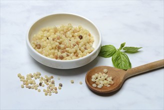 Cooked fregola in bowl with wooden spoon, pasta variety from Sardinia, Italy, Europe