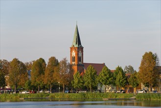 A church on the shore of a lake surrounded by colourful trees, Maria Meeresstern church, old town