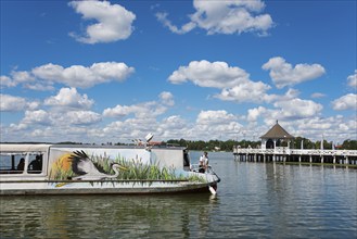 A boat on a lake with a pier and pavilion under a blue sky, Drawenzsee, Jezioro Drweckie, Ostroda,