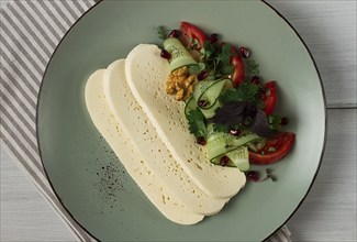 Sliced Imeruli cheese, Georgian cheese, with vegetables, top view, no people