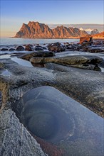 Rocky coast in front of steep mountains in the evening light, winter, the eye, Utakleiv, Vestoya,