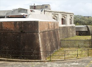 Two people using binoculars standing inside fortress tower wall, Landguard Fort, Felixstowe,