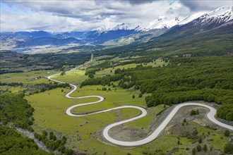 Road Carretera Austral winding down into the valley of Villa Cerro Castillo, snowcapped mountains