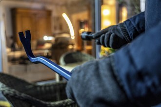 Symbolic image of a burglary, perpetrator spies on a flat from the garden side