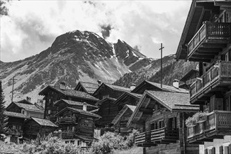 Nested old wooden houses, in the background the summit of the mountain Scex de Marenda, historic