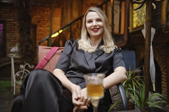 Lovely woman is captured in a moment of relaxation with a glass of beer at a cozy outdoor cafe