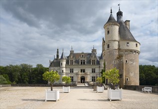 Imposing castle with ornamental towers and white tubs on a gravel path, Chenonceau Castle, Château