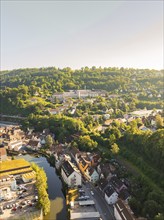 Hospital with city view from the air along a river, surrounded by hilly forests and roads, Calw,