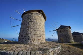 Two old stone windmills under a clear blue sky in a natural landscape, windmills, on a ridge, above