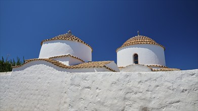 Two white-painted church towers with round, red-tiled roofs against a bright blue sky, Chora, Old