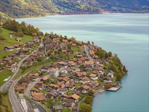 Hilly village with houses and streets on the edge of a lake, surrounded by mountains, Lake Brienz.