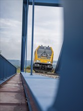 Train approaching from behind blue subway on rails, track construction, rail delivery for Hermann