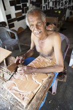 Sri Lankan man with bare upper body carving a wooden picture, Kandy, Central Province, Sri Lanka,