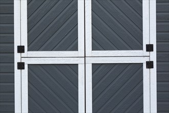 Individual small square doors on storage shed cladded with grey and white trim canexel wood