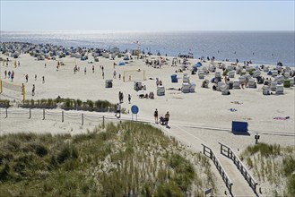 View over the dune landscape to the beach with beach chairs and areas for sports, blue sky, North